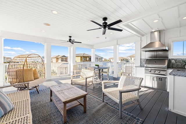 interior space featuring a wooden deck, grilling area, ceiling fan, and an outdoor kitchen