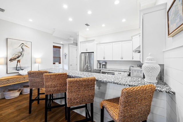 kitchen with light stone countertops, high quality fridge, and a kitchen bar