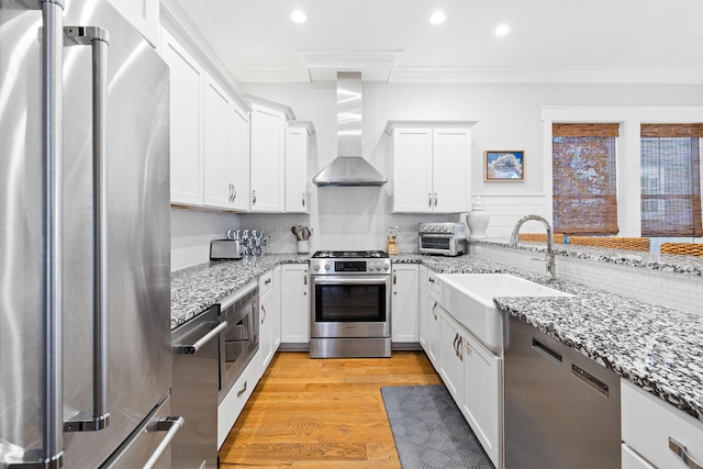 kitchen with white cabinetry, appliances with stainless steel finishes, sink, and wall chimney exhaust hood