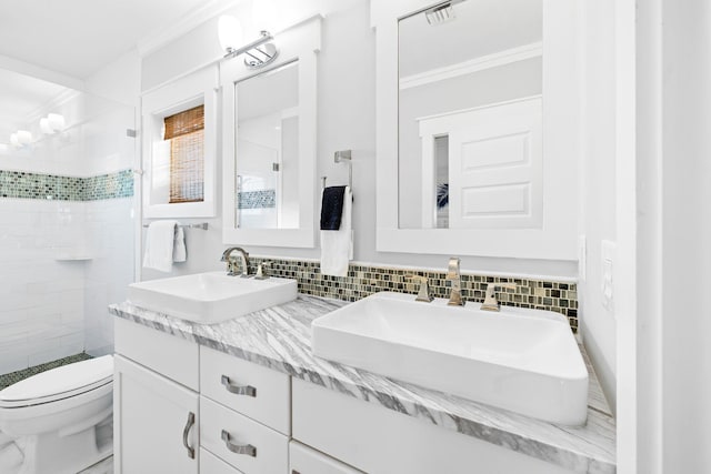 bathroom featuring tasteful backsplash, vanity, a tile shower, and toilet