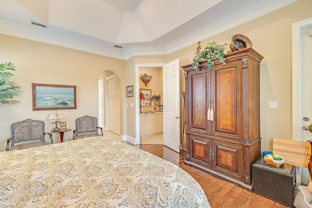 bedroom featuring dark hardwood / wood-style flooring, ornamental molding, and ensuite bathroom