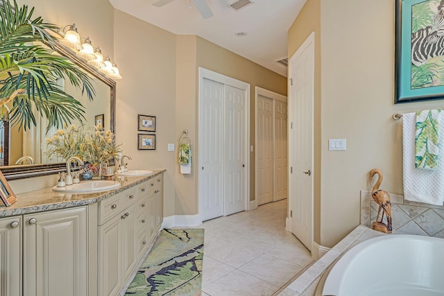 bathroom with tile patterned flooring, vanity, ceiling fan, and tiled tub