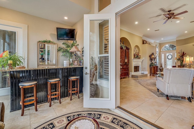 bar featuring crown molding, light tile patterned floors, and ceiling fan