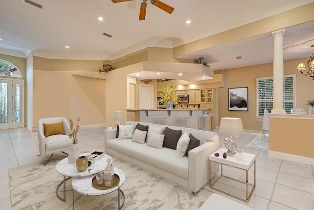 tiled living room with crown molding, ceiling fan with notable chandelier, and decorative columns