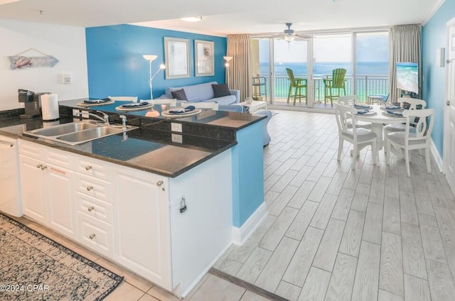 kitchen featuring floor to ceiling windows, sink, a water view, white cabinetry, and ceiling fan