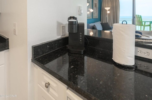 room details featuring white cabinetry, pendant lighting, and dark stone countertops