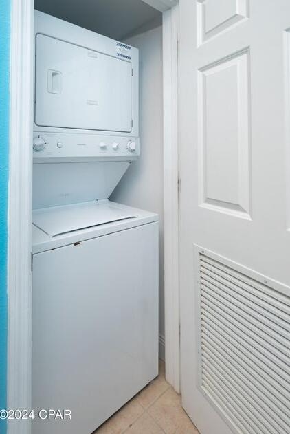 laundry room with stacked washer / drying machine and light tile patterned floors