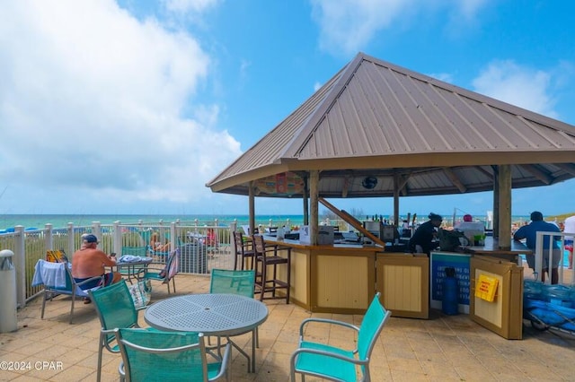 view of patio / terrace featuring a gazebo, a water view, and a beach view