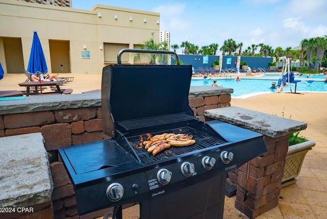 view of patio / terrace featuring area for grilling, a community pool, and a fire pit