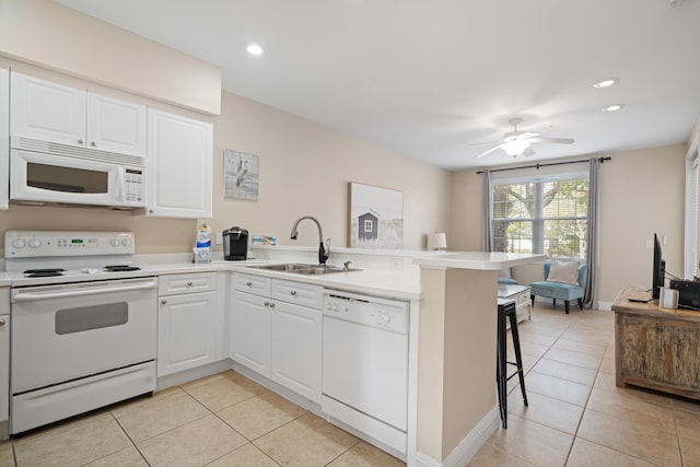 kitchen with sink, white appliances, a breakfast bar, white cabinetry, and kitchen peninsula