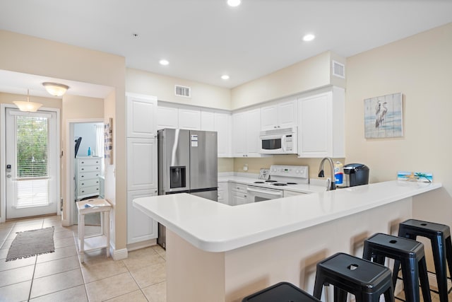 kitchen featuring white cabinetry, white appliances, kitchen peninsula, and a breakfast bar