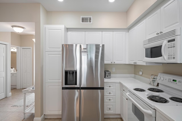 kitchen featuring light tile patterned floors, white appliances, and white cabinets