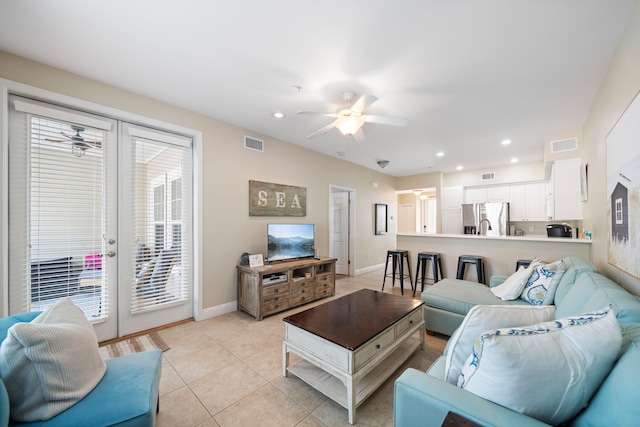 tiled living room with ceiling fan and french doors