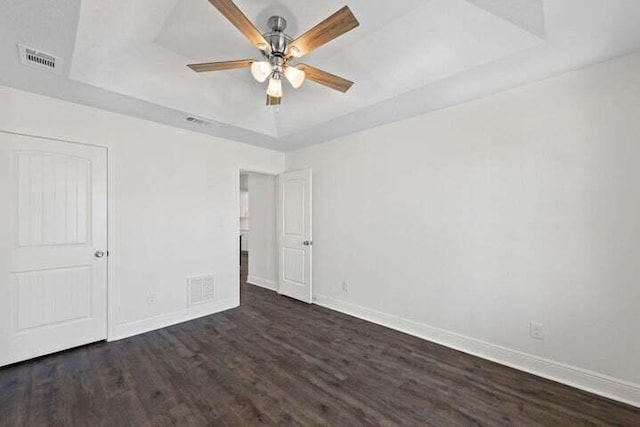 unfurnished bedroom with dark wood-type flooring, ceiling fan, and a tray ceiling