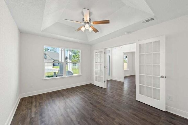 spare room featuring french doors, ceiling fan, dark hardwood / wood-style flooring, and a raised ceiling