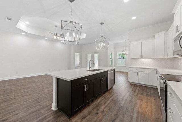 kitchen featuring stainless steel appliances, decorative light fixtures, a center island with sink, and white cabinets