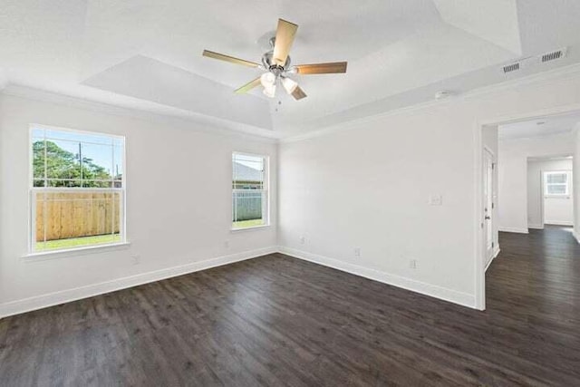 empty room with ornamental molding, ceiling fan, dark hardwood / wood-style flooring, and a tray ceiling