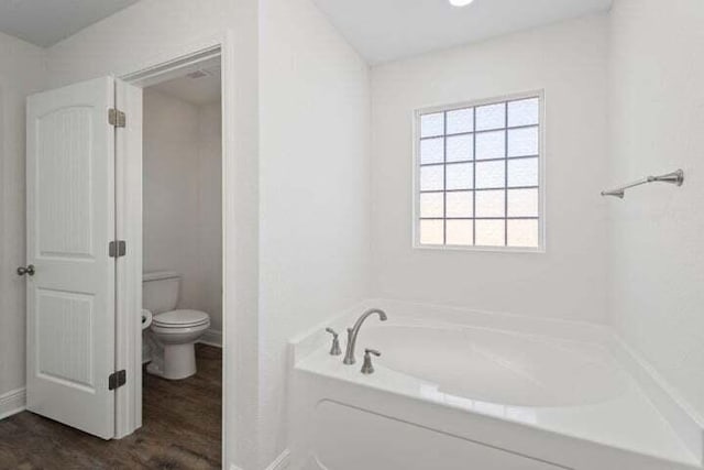 bathroom featuring hardwood / wood-style flooring, toilet, and a bathing tub