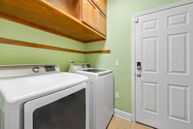 laundry area featuring cabinets, washing machine and dryer, and light tile patterned floors