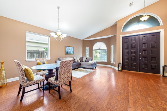 dining area with an inviting chandelier, hardwood / wood-style flooring, and high vaulted ceiling