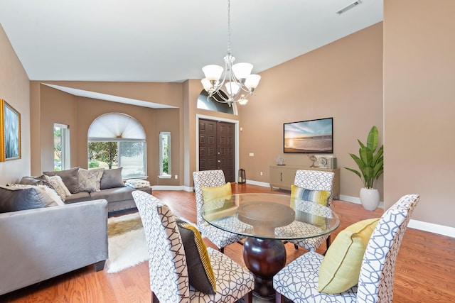 dining area featuring an inviting chandelier, high vaulted ceiling, and light wood-type flooring