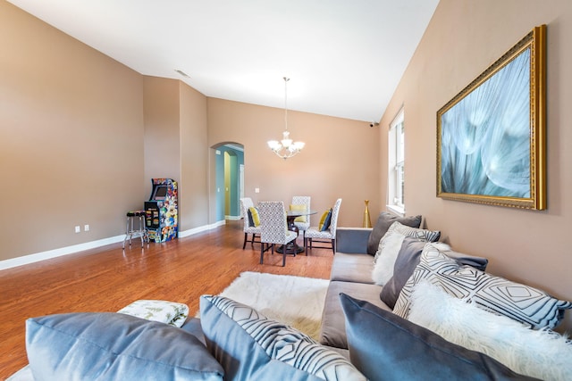 living room with an inviting chandelier, wood-type flooring, and vaulted ceiling