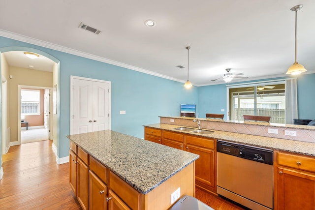 kitchen with sink, decorative light fixtures, a center island, dishwasher, and light stone countertops