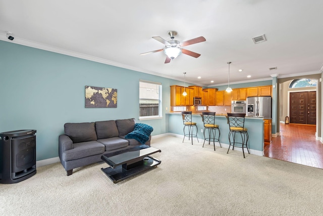 living room featuring light colored carpet, ornamental molding, and ceiling fan