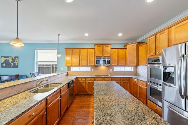 kitchen with appliances with stainless steel finishes, sink, backsplash, hanging light fixtures, and light stone counters