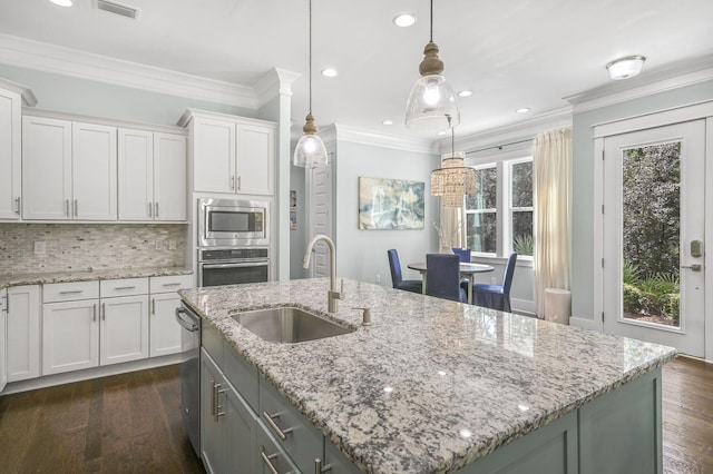 kitchen with appliances with stainless steel finishes, a center island with sink, and white cabinets