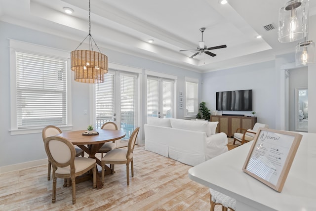 dining space with a tray ceiling, light hardwood / wood-style floors, and ceiling fan