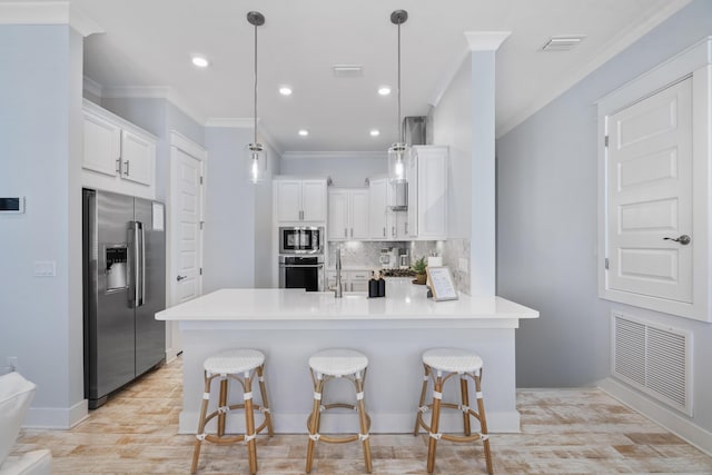 kitchen featuring stainless steel appliances, hanging light fixtures, a breakfast bar area, and white cabinets