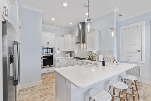 kitchen featuring sink, hanging light fixtures, appliances with stainless steel finishes, a kitchen breakfast bar, and kitchen peninsula