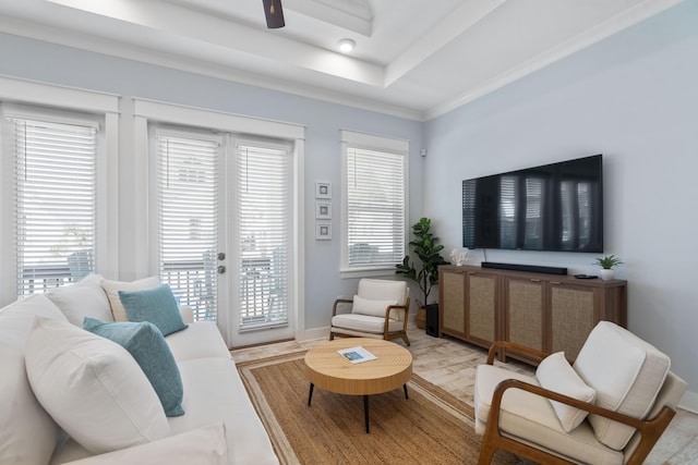 living room with light hardwood / wood-style flooring, a tray ceiling, a wealth of natural light, and french doors