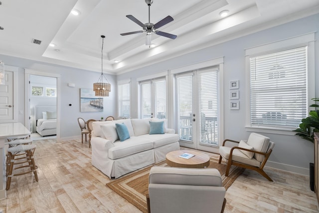 living room with a tray ceiling, a wealth of natural light, and light wood-type flooring