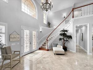 entrance foyer featuring an inviting chandelier, a towering ceiling, and french doors