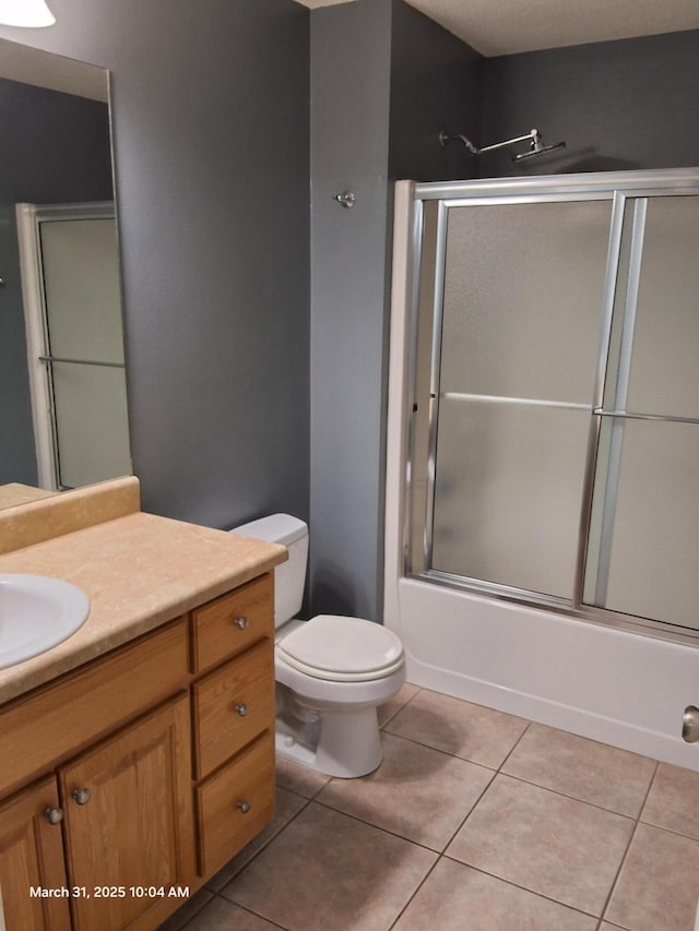full bath featuring bath / shower combo with glass door, toilet, tile patterned flooring, and vanity