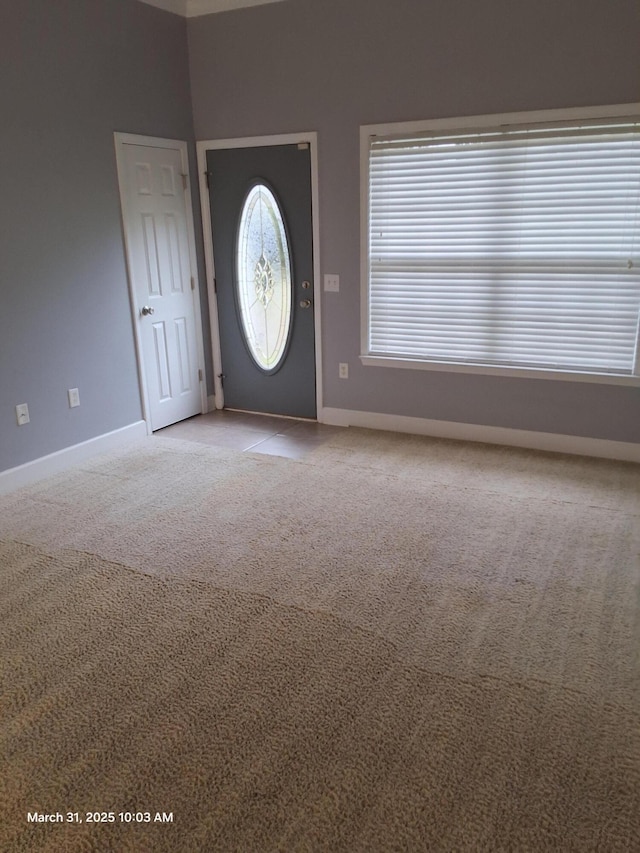 foyer entrance featuring baseboards and light colored carpet