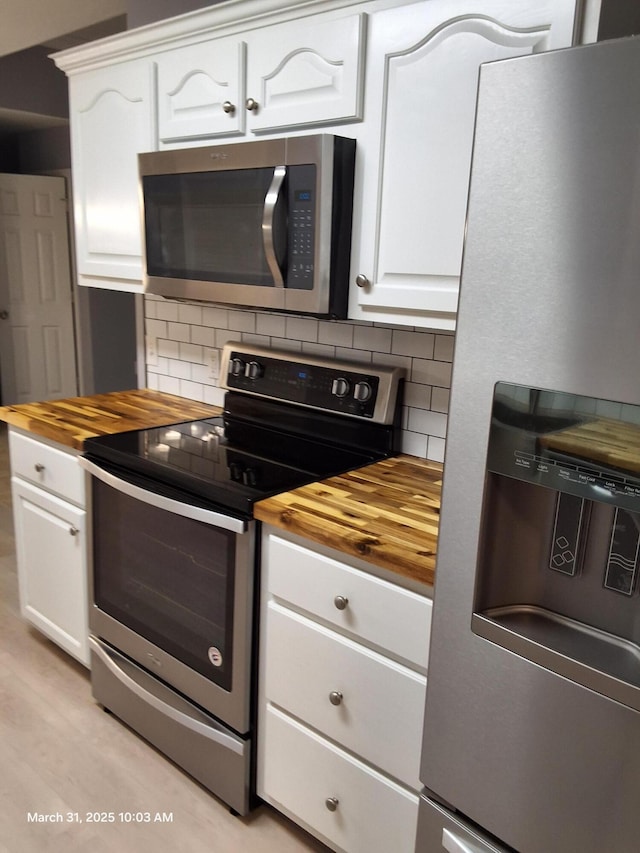 kitchen with butcher block counters, tasteful backsplash, and appliances with stainless steel finishes