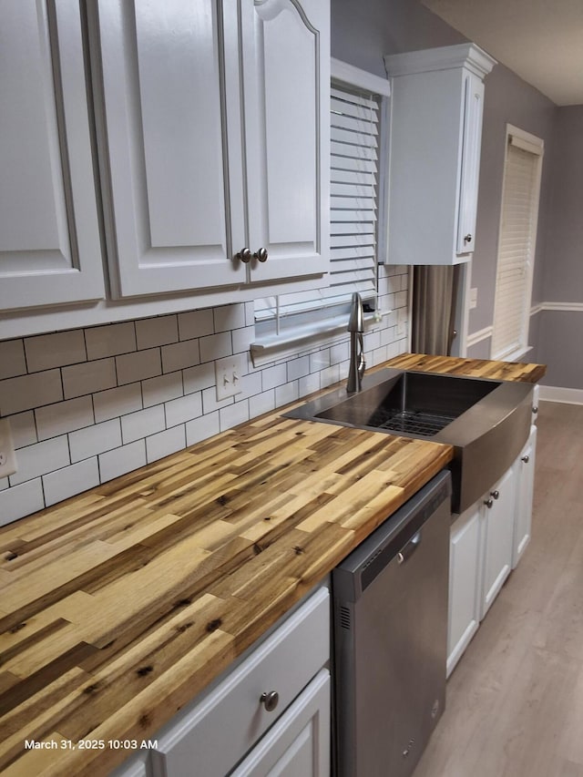 kitchen featuring a sink, white cabinetry, stainless steel dishwasher, butcher block counters, and light wood-style floors