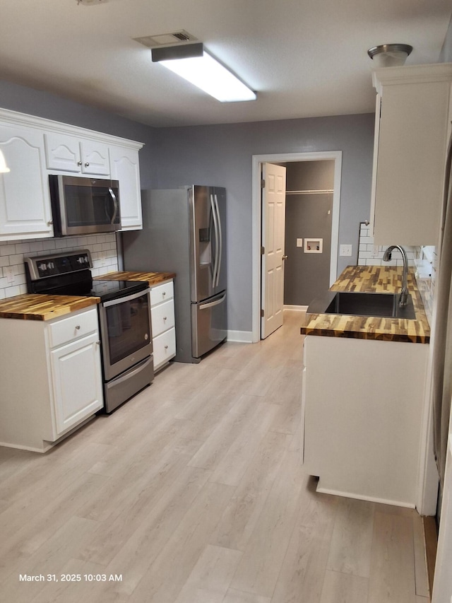 kitchen with white cabinetry, wooden counters, a sink, and appliances with stainless steel finishes