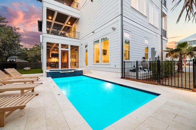 pool at dusk with a patio area and an in ground hot tub