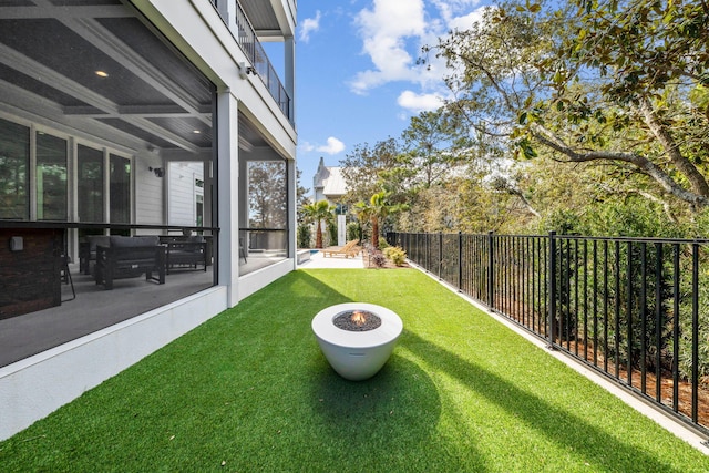 view of yard featuring a sunroom and an outdoor fire pit