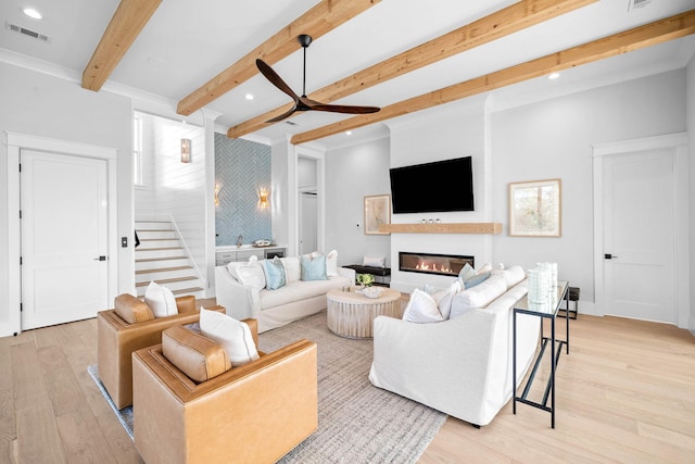 living room featuring beam ceiling, light hardwood / wood-style flooring, and ceiling fan