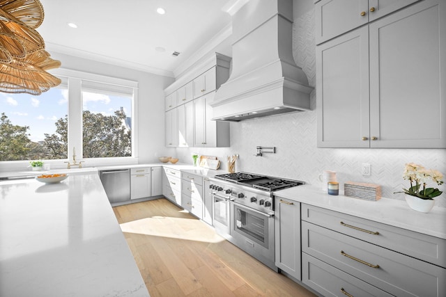 kitchen featuring crown molding, appliances with stainless steel finishes, gray cabinetry, decorative backsplash, and custom exhaust hood