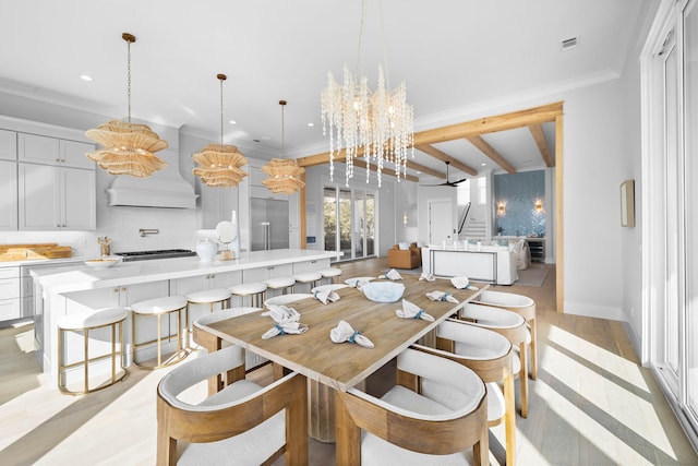 dining space featuring ornamental molding, a notable chandelier, beam ceiling, and light hardwood / wood-style flooring