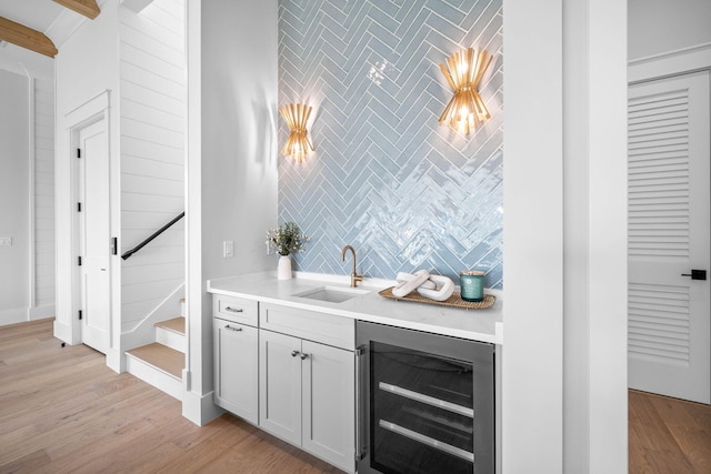 bar with sink, wine cooler, light hardwood / wood-style floors, and decorative backsplash