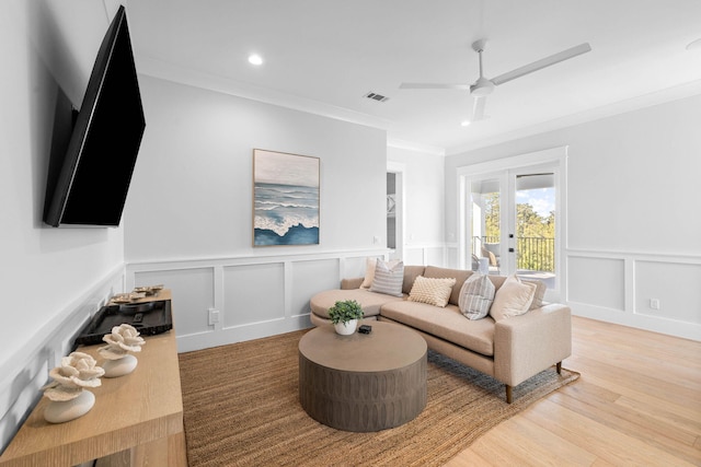 living room featuring ornamental molding, light hardwood / wood-style floors, ceiling fan, and french doors