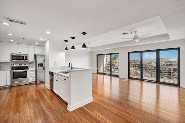 kitchen with white cabinetry, appliances with stainless steel finishes, sink, and decorative light fixtures