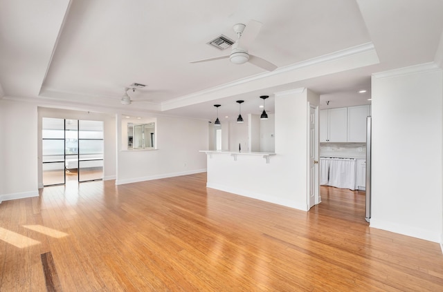 unfurnished living room featuring crown molding, light wood-type flooring, ceiling fan, and a tray ceiling